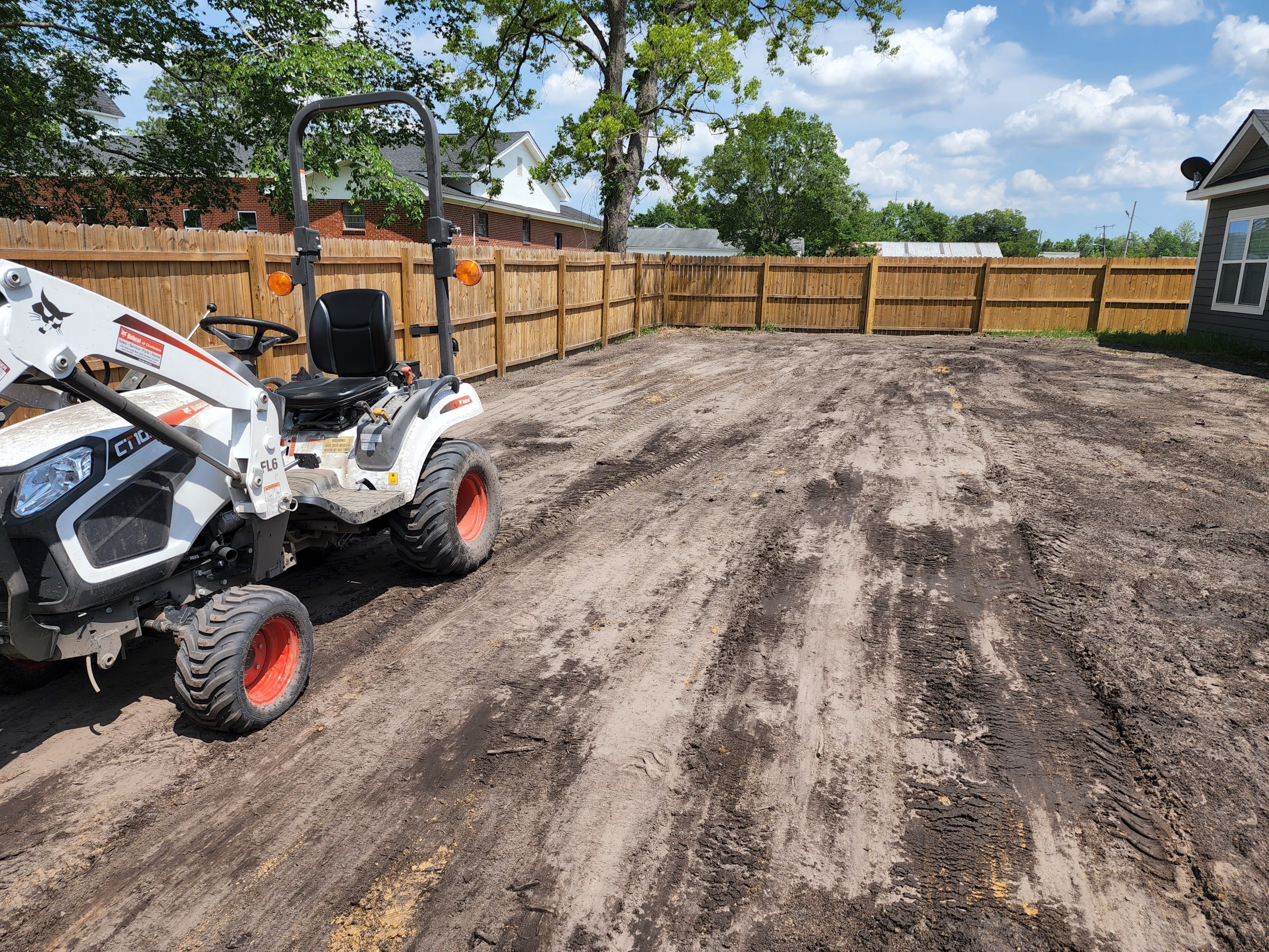 A tractor parked in the dirt near a fence.